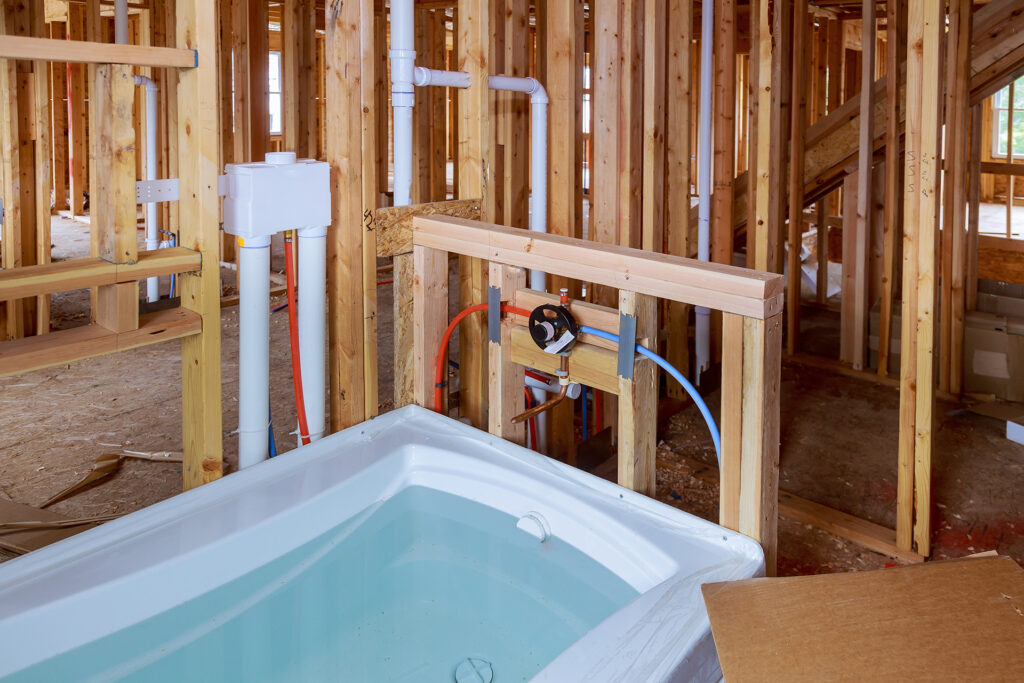 new construction bathtub and red and blue pex pipes